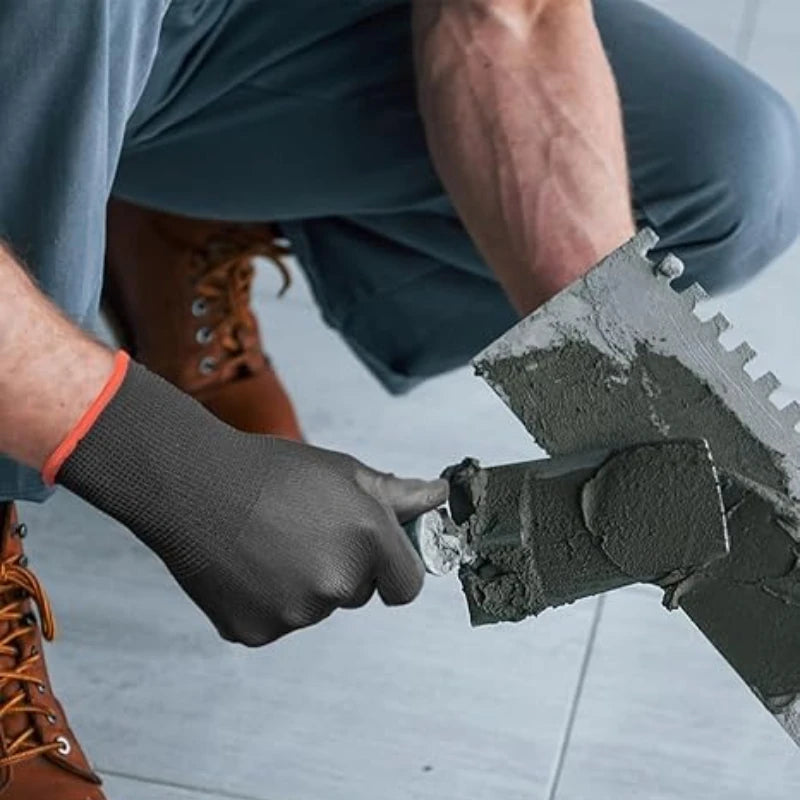 Person applying cement to a brick with a trowel on a tiled floor.